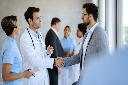 Clinical researcher shaking hands with a healthcare partner during a clinical trial collaboration at STK Life.