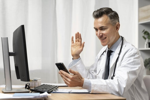 Doctor conducting a virtual eVisit consultation using a smartphone and computer during a clinical trial.